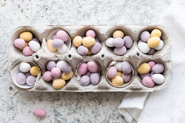 Easter composition with mini chocolate eggs in pastel colors on grey concrete background. Happy Easter Holidays. Top view.