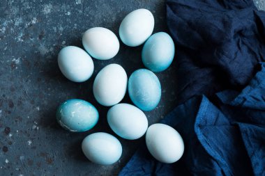 Mavi Paskalya yumurtaları koyu mavi beton arka planda doğal boya kırmızısı lahanayla boyanmış. Bir sıra mavi ombre paskalya yumurtası. Gıda boyasıyla doğal ekolojik lekeler. Üst görünüm.