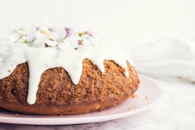 Çiçeklerle süslenmiş paskalya pastası ve beyaz mermer arka planda mini çikolata yumurtaları. Mutlu Paskalyalar..