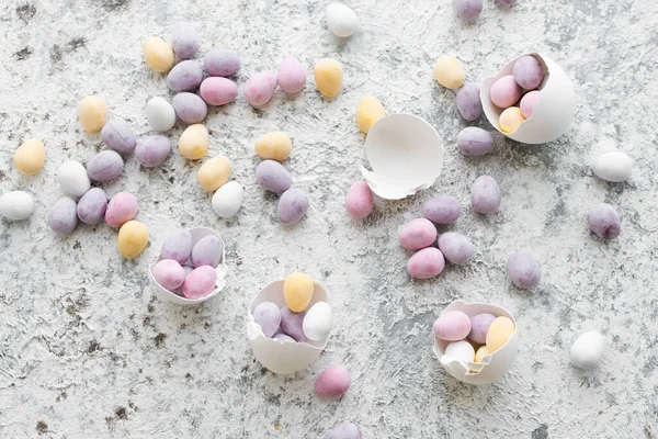 Easter composition with mini chocolate eggs in pastel colors on grey concrete background. Happy Easter Holidays. Top view.