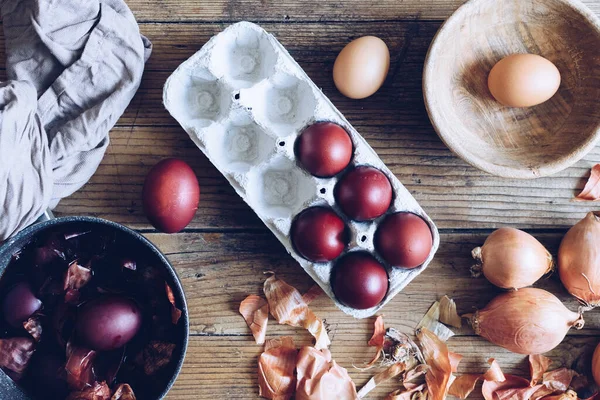 Dyed Easter eggs painted with natural dye onion on rustic wooden background. Process of dyeing eggs with natural paints for Easter. Natural ecological staining with food coloring. Top view.