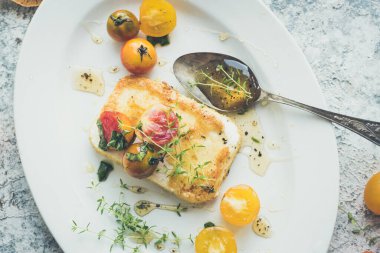 Ekmek kırıntılarıyla kaplanmış tavada tuzlu peynir, biberli kekik balı ve renkli domatesli kirazlı. Vejetaryen sağlıklı gıda konsepti. Üst görünüm.