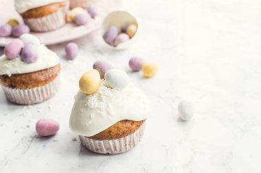 Beyaz mermer arka planda mini çikolatalı yumurtalarla süslenmiş Paskalya kekleri. Mutlu Paskalyalar. Boşluğu kopyala.