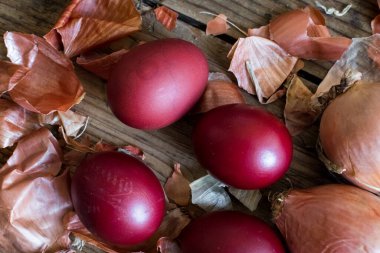 Kırsal ahşap arka planda doğal boya soğanıyla boyanmış Paskalya yumurtaları. Paskalya için doğal boya ile yumurta boyama işlemi. Gıda boyasıyla doğal ekolojik lekeler. Üst görünüm.