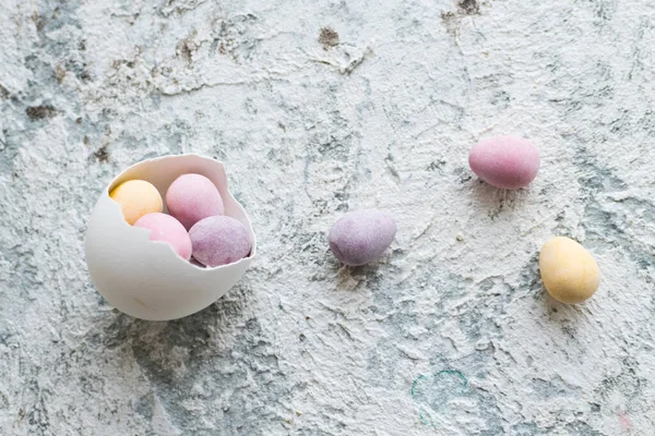 Easter composition with mini chocolate eggs in pastel colors on grey concrete background. Happy Easter Holidays. Top view. Copy space.