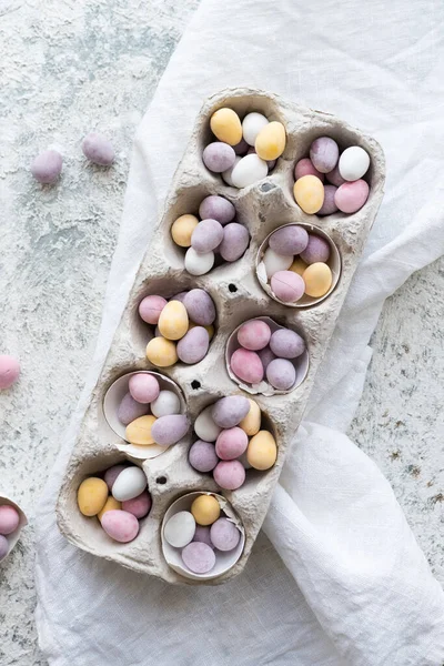 Easter composition with mini chocolate eggs in pastel colors on grey concrete background. Happy Easter Holidays. Top view.