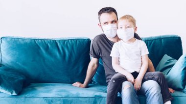 Genç, karantinaya alınmış tıbbi maskeli Coronavirus ailesi. Evde kalma çağrısı salgını durdurur. Kendini izole etmek bir çözüm. Coperid 19 'a dikkat et. Baba ve oğul milenyumu.