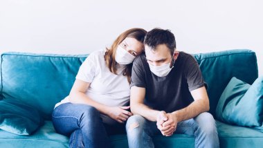 Hüzünlü hüzünlü karantinaya alınmış tıbbi maskeli koronavirüs ailesi. Korona virüsü yüzünden endişe ve korku içindeki insanlar. Evde tek başına kal. Hamile kadın ve erkek milenyumu.