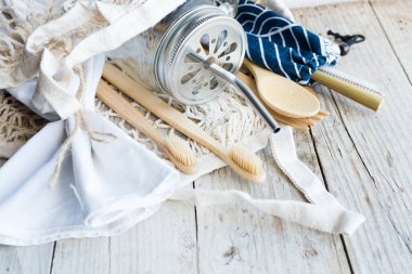 Sıfır atık. Pamuk torbaları, cam kavanoz, bambu çatal bıçak takımı ve tahta arka planda diş fırçası. Sürdürülebilir yaşam. Çevre dostu plastik eşyalar.