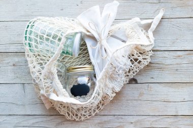 Yeniden kullanılabilir pamuk torbası ve tahta arka planda cam kavanozlar. Sıfır atık. Sürdürülebilir yaşam, plastiksiz konsept. Eko dostu plastik eşyalar. Üst Manzara. Boşluğu kopyala.