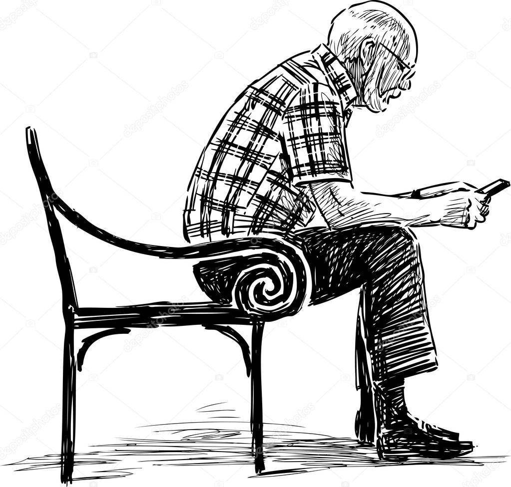 A senior man with a mobile phone sits on a park bench
