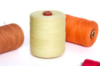 Dört makara beyaz bir arka plan üzerinde renkli iplik. İş parçacığı sarı, turuncu, kırmızı ve kahverengi biriktirme.