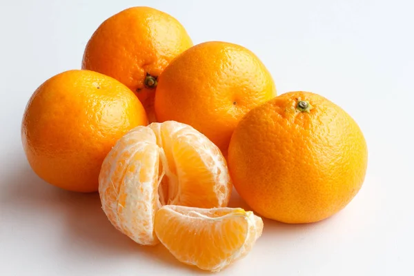 Mandarynka na białym tle. Pięciu Mandarin leżą obok siebie. Jeden bez skórki mandarynki i plasterek mandarynka. — Zdjęcie stockowe