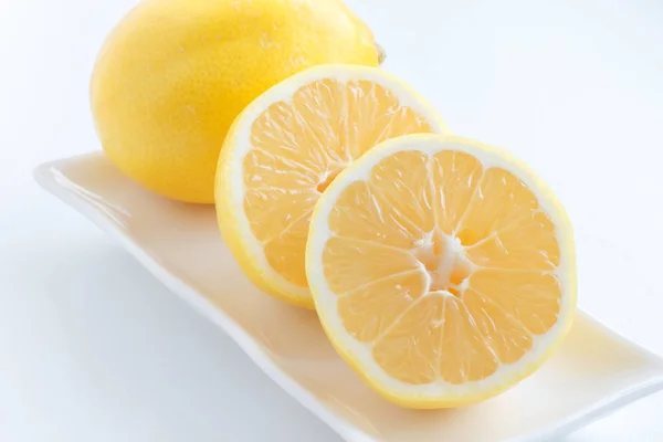 Citron halveras. Två halvor av citron ligga bredvid en citron på plattan. — Stockfoto