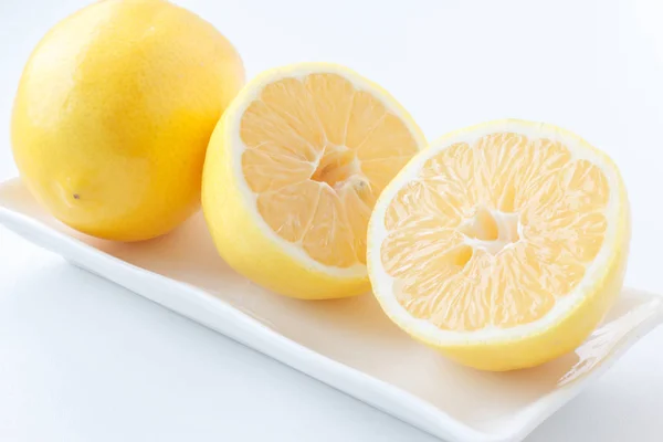 Citron halveras. Två halvor av citron ligga bredvid en citron på plattan. — Stockfoto