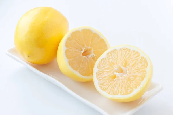 Citron coupé en deux. Deux moitiés de citron couché à côté d'un citron sur l'assiette . — Photo