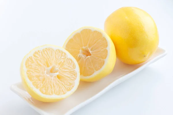 Citron halveras. Två halvor av citron ligga bredvid en citron på plattan. — Stockfoto