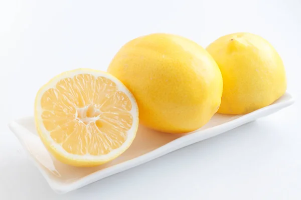 Citron halveras. Två halvor av citron ligga bredvid en citron på plattan. — Stockfoto