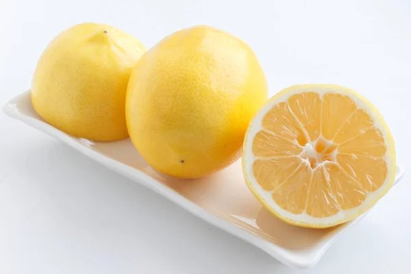 Citron coupé en deux. Deux moitiés de citron couché à côté d'un citron sur l'assiette . — Photo