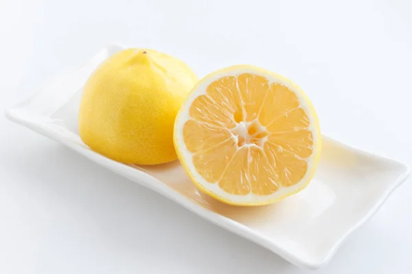 Citron coupé en deux. Les deux moitiés du citron couché sur l'assiette . — Photo