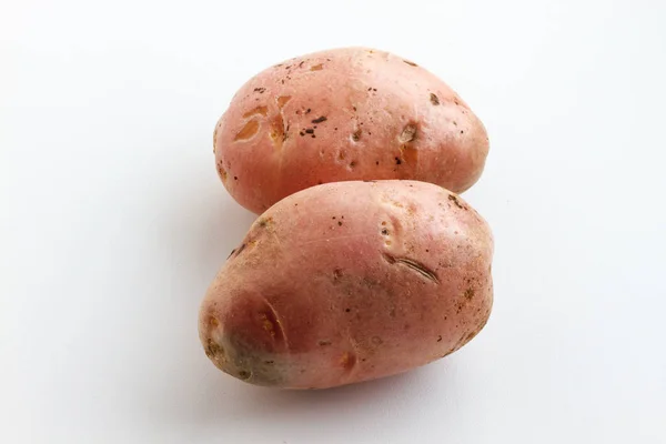 En massa smutsiga potatis på en vit bakgrund. Potatis utspridda på en vit bakgrund. — Stockfoto