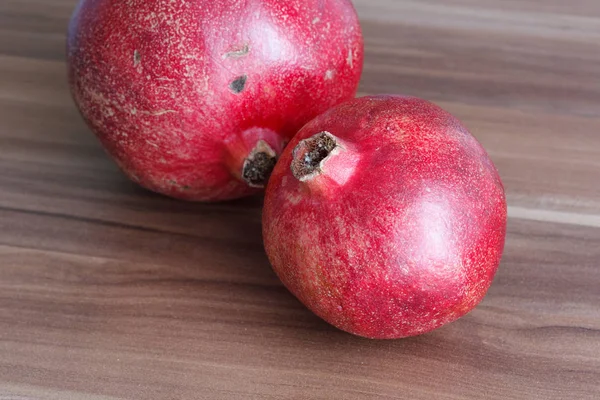 Zwei leuchtend rote und saftige Granatapfelfrüchte auf einem Holztisch. — Stockfoto