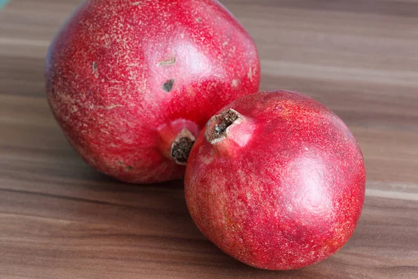 Два ярко-красных и сочных фрукта граната на деревянном столе . — стоковое фото