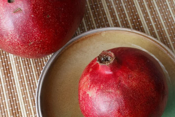 Спелые красные гранатовые фрукты лежат на глиняной тарелке . — стоковое фото