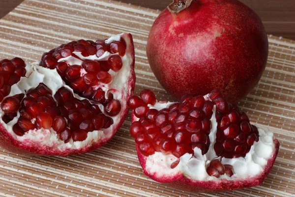 Pomegranate fruit cut in half. Bright juicy ripe pomegranate seeds. — Stock Photo, Image