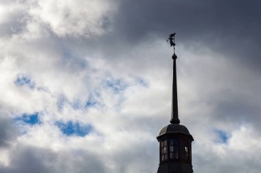 Bir manastır kulesinde trompet çalan bir melek figürü dramatik bir gökyüzüne karşı.