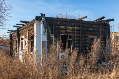 Yangından zarar gören ahşap bir evin kalıntıları. Mavi gökyüzüne çarpan yanmış kirişler.