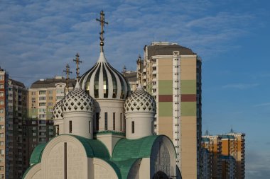 Yüksek binaların ve mavi gökyüzünün arka planına karşı inşa halindeki bir Ortodoks kilisesinin kubbeleri