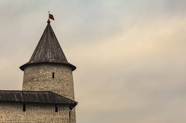 Watchtower and a fragment of the fortress wall of an old fortress against a stormy sky