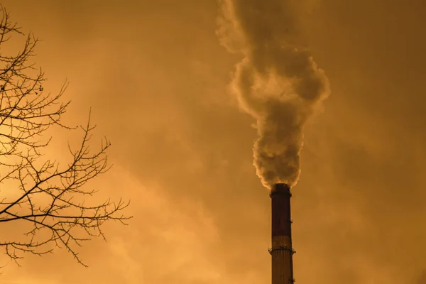 Smoky factory chimney against smog blurred sky