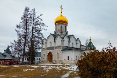 Altın kubbeleri olan eski bir Ortodoks kilisesi yağmurlu bir gökyüzüne karşı tozlu bir kar tepesinde duruyor.