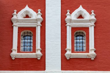 İki beyaz sıva pencereli eski bir kırmızı kilisenin duvarı.