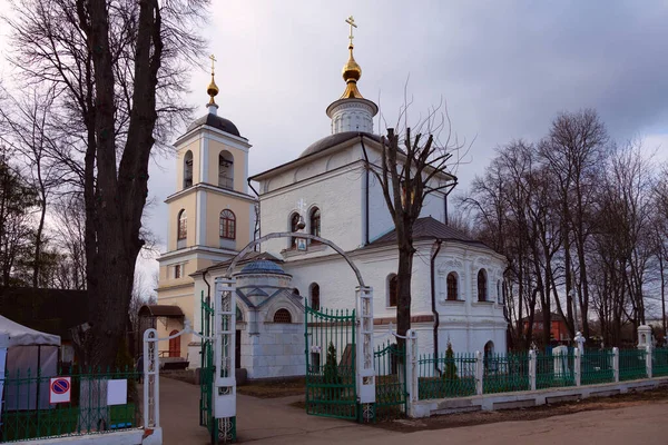 An old white-stone Orthodox church surrounded by a forged fence with a stone base