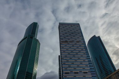 Bulutlu gökyüzüne doğru yönelen cam ve beton gökdelenler