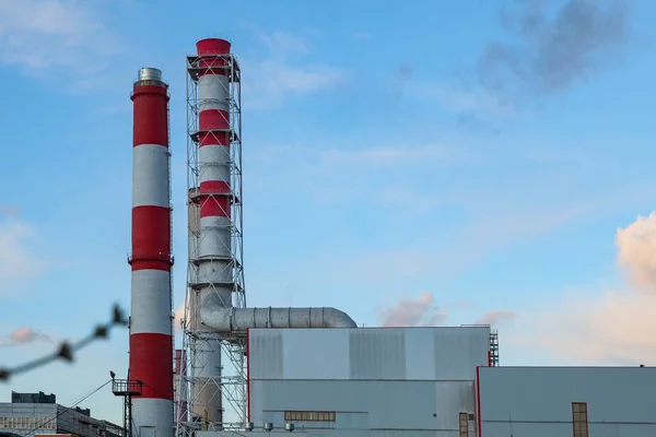 Factory building with two factory chimneys against a blue sky with light clouds