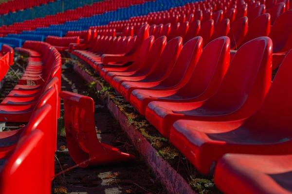 放棄されたサッカースタジアムのプラスチック製の椅子が列に並んでいます 椅子の一つが壊れて地面に横たわっている — ストック写真