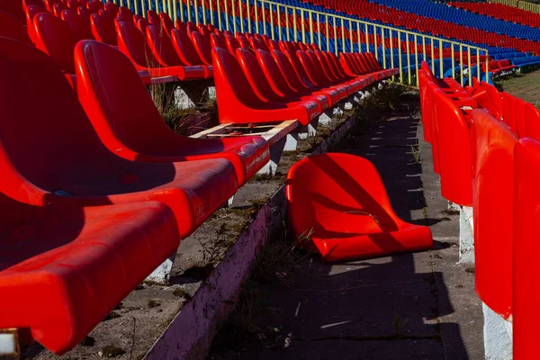 成長過ぎたスタジアムの古いプラスチックシートの行 椅子の一つが地面に横たわっている — ストック写真