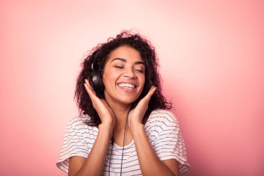 Müzik ve pembe bir arka plan üzerinde dans afro saç listining ile güzel kadın