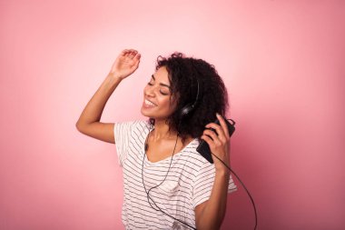 Müzik ve pembe bir arka plan üzerinde dans afro saç listining ile güzel kadın