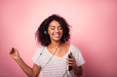 Müzik ve pembe bir arka plan üzerinde dans afro saç listining ile güzel kadın