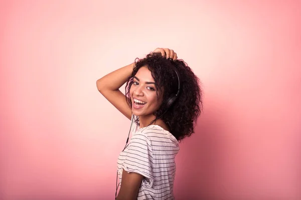 Belle femme avec des cheveux afro listining à la musique et la danse sur un fond rose — Photo