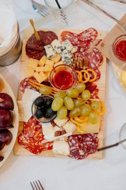 Çeşitli parti aperatifler. Dilimlenmiş sosis farklı, peynir ve üzüm bir ahşap tepsi. Parti için yemek. mavi peynir