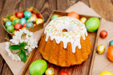 Paskalya kompozisyonu. Beyaz jöleli Paskalya pastası ve ahşap masaya boyanmış yumurtalar..