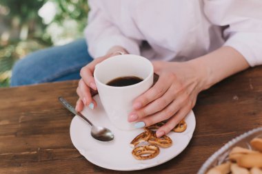 Anında kahve. Bir kadın hazır kahve granüllerini beyaz bir fincana dolduruyor. Sabah mutfakta..