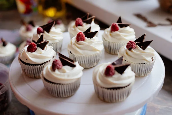 Chocolate cupcakes. Homemade chocolate muffins. The process of making homemade chocolate cupcakes with whipped cream and decorated with chocolate and raspberry pieces.