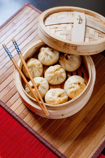 Steamed dumplings Dim Sum in bamboo steamer on bamboo wooden background. Chinese food.